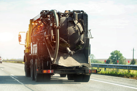 A concrete mixer with a concrete delivery hose on a country road against the backdrop of the sunset