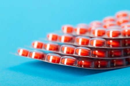 Stack of red pills on blue background, close-up. Concept of vitamins in pharmaceuticals. Copy space for textの写真素材
