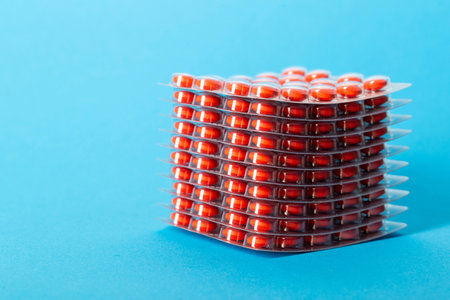 Stack of pills blisters with red pills on blue background. Concept of rifamycin antibiotics in the...