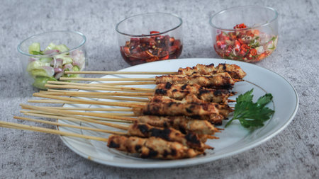 A plate of fresh satay served with pickles, soy sauce and sambal matah in the room, their vibrant colors and aromas add to its delectable appeal. side viewの写真素材