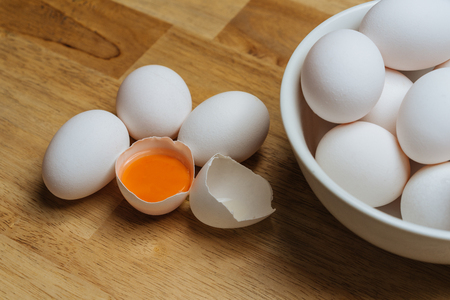 Chicken eggs in bowl and a cracked openの写真素材