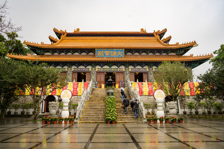 Ngong Ping village, Lantau island - Hong Kong. April 25 - 2017: Some tourists are visiting Po Lin monastary main hall during rain shower and cloudy morningのeditorial素材