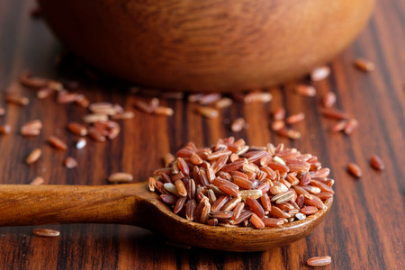Red rice grain on wooden spoon with wooden backgroundの写真素材