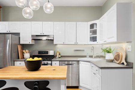 A kitchen detail with white cabinets, wood butcher block island, green walls, and a light fixture...