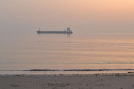 sunset with ship westerschelde beach near Zoutelandeの写真素材