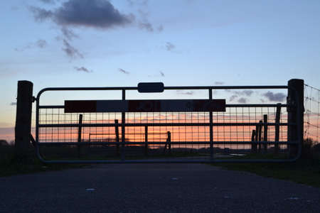 sunset fence near meadow on dike of river Oude IJsselの写真素材