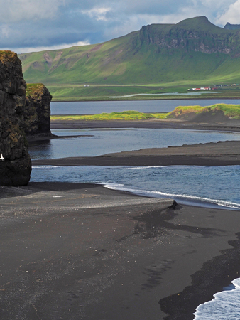 magic iceland landscape with black lava sand and green eroded hills and rocksの写真素材