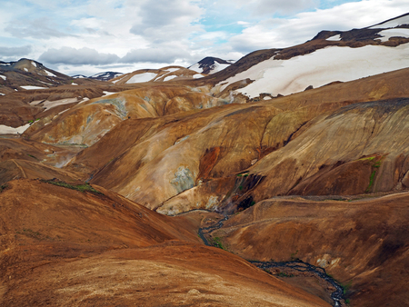colourfull rhyoliet Kerlingarfj?ll volcanic mountains in geothermal area in iceland with snow tangues and hot river streamの写真素材
