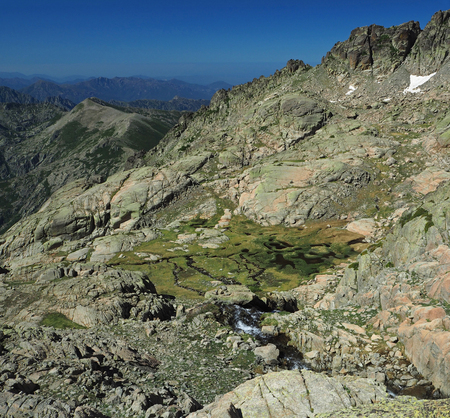 Mountain wild spring on the green meadow and rocksの写真素材