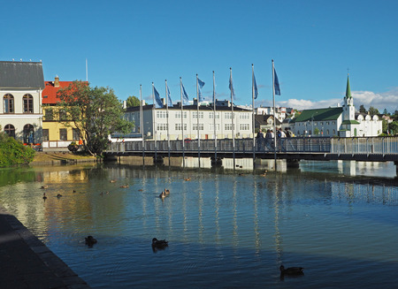 Reykjavik city center - bridge over the pond with ducks, church and people on a sunny day, Icelandの写真素材