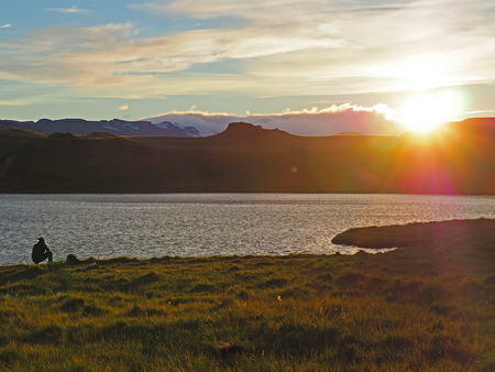 man fishing on Iceland lake Thveit near Hofn on sunset with snow mountains backgroundの写真素材