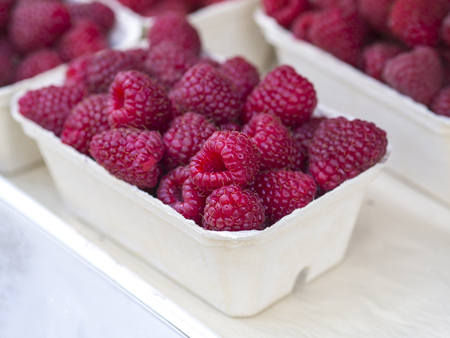 close up fresh raspberry in a white paper box on white backgroundの写真素材