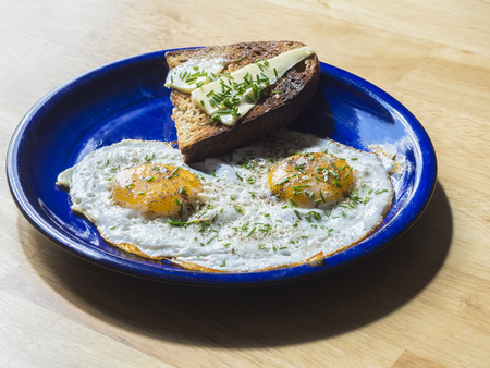 two fried eggs sunny side up egg on blue ceramic plate on wooden tableの写真素材