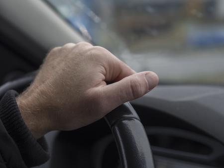 close up man hand holding streering wheel view from inside of th car defocused backgroundの写真素材