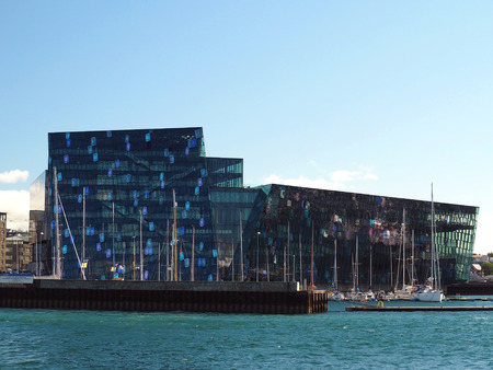 Iceland, Reykjavik, August 3, 2016: Harpa Reykjavik Concert Hall and Conference Centre view from sea with yachts and blue skyのeditorial素材