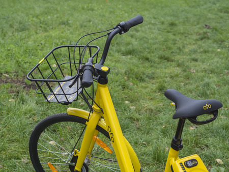 Czech republic, Prague, Holesovice, November 13, 2017:yellow bikecycle for sharing rental unlock by mobile app on smarphone ecological city transport on green grass backgroundのeditorial素材