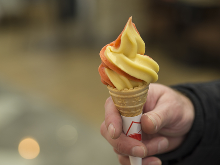 man hand holding giving ice scream cone bokeh background