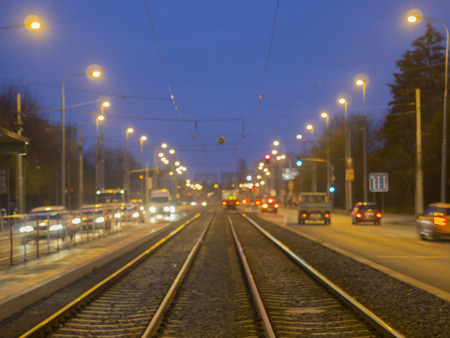 colorful blurred street tramway line with traffic lights with defocused tram and cars during twilingの写真素材