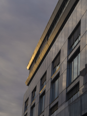 detail of gray office building with big windows in golden evening light
