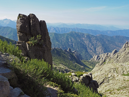 beautiful scenery of high mountain lake in corsician alpes with rocks green bushes and blue sky background on gr20 famous trekの写真素材