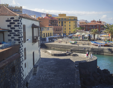 Spain, Canary islands, Tenerife, Puerto de la cruz, December 23, 2017: view on city center with old building on sea front, relaxing tourist people, ship,palm trees and hotels on promenadeのeditorial素材