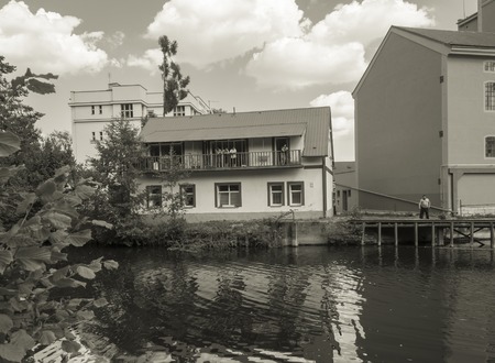 Czech Republic,Jizera, July 28, 2018: old houses on Jizera river bank, gypsy people looking from balcony, man standing on molo, view from river, vintage style look, sepia toningのeditorial素材