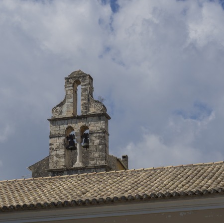 Traditional Greek church stone bell tower and roof in Corfu town, Corfu Greece, blue sky white...