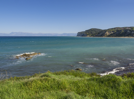 View on agios stefanos beach and bay with lush green grass and steep cliffs, north east coast of Corfu in Greece, summer day blue skyの写真素材