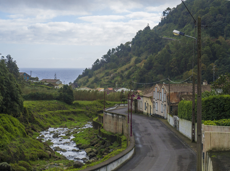Road in old small village Faial da Terra with cascading river and sea horizon, Sao Miguel, Azoresの写真素材