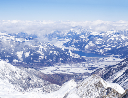 Winter landscape with snow covered slopes and blue sky, with Aerial view of Zell am See lake from the top of Kitzsteinhorn mountain on . Kaprun ski resort, National Park Hohe Tauern, Austrian Alps, Europe.の写真素材