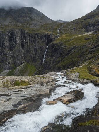 View point platform on Trollstigen or Trolls Path with green valley and waterfall at massif...