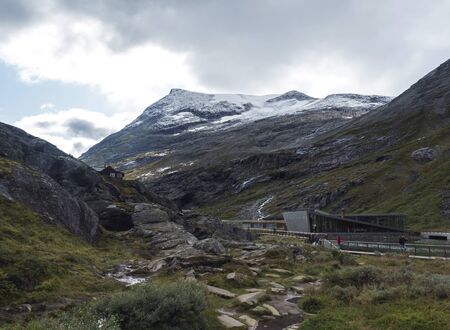 Andalsnes, Norway, September 7, 2019: Modern building Trollstigen Visitor Centre and Restaurant at view point on Trolls Path with tourist people at massif Trolltindene, Norway. Cloudy white sky clouds.のeditorial素材