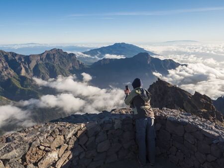 Man tourist takeing picture of volcanic crater Caldera de Taburiente Natoional Park seen from mountain peakの写真素材