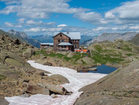 Stubai Valley, Innsbruck-Land, Tyrol, Austria, July 5, 2020: View of Bremer Hutte, an alpine mountian wooden hut with blue lake from melting snow tongues, moutain peaks, sunny summer day.のeditorial素材