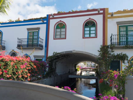 Colorful buildings of Puerto de Mogan with sea canal and boat and flowers. Traditional colonial architecture of small fishing village port, favorite tourist place. Gran Canaria, Canary Islands, Spainの写真素材