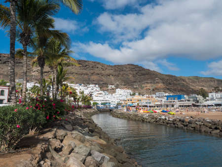 Puerto de Mogan, Gran Canaria, Canary Islands, Spain December 18, 2020: View on the public beach with golden sand and apartments in popular holiday village Puerto de Mogan at sunny dayのeditorial素材