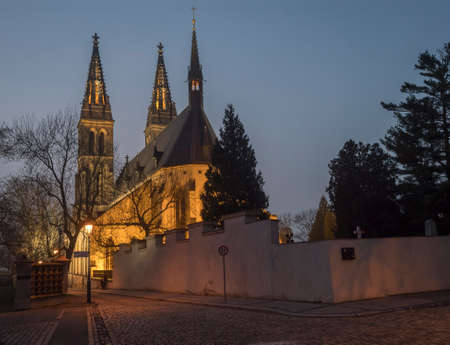 Czech Republic, Prague, February 23, 2021: illuminated Basilica of St. Peter and Paul, gothic cathedral church on Vysehrad. Cobbled street by night with lanterns.のeditorial素材
