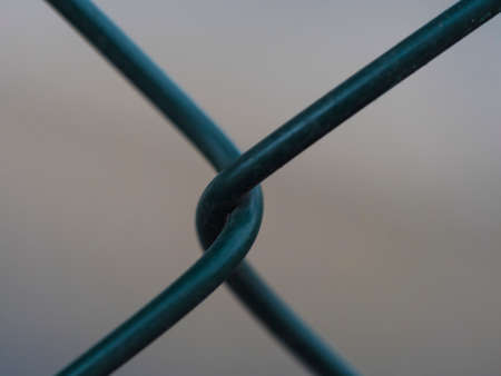 Close up of green metal wire fence twist on beige bokeh background. Macro photograph of iron mesh. Selective focusの写真素材