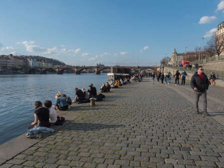 Prague, Czech Republic, March 26, 2021: The embankment of river Vltava called Naplavka, with crowd of people at spring sunny day during covid pandemic. In the background Palacky Bridgeのeditorial素材