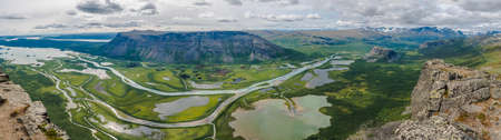 Aerial panoramic scenic view from Skierffe rock summit on glacial Rapadalen river delta valley at Sarek national park with meanders, lakes, mountains, birch trees. Summer day landscape Sweden Laplandの写真素材
