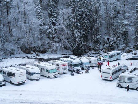 Spindleruv Mlyn, Czech republic, December 5, 2021: Winter view of car park with parked snow-covered campers at Spindleruv Mlyn, popular tourist destination, and ski resort. Cloudy dayのeditorial素材