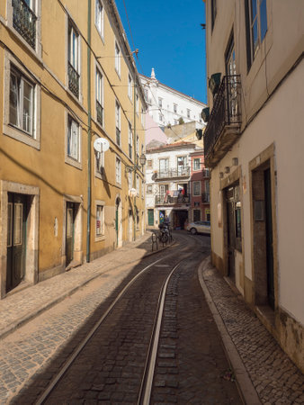 Lisbon, Portugal, October 24, 2021: View of steep narrow Lisbon streets with tram rails at medieval quarter Alfamaのeditorial素材