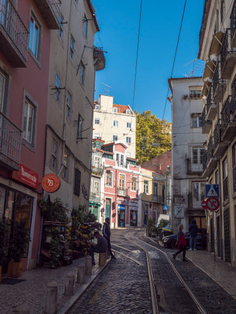 Lisbon, Portugal, October 24, 2021: View of steep narrow Lisbon streets with tram rails at medieval quarter Alfamaのeditorial素材
