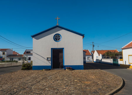 Almograve, Odemira - Longueira, Portugal, October 26, 2021: View of church Igreja Matriz de Almograve at white, yellow and blue traditional Portuguese style. Sunny day, clear blue skyのeditorial素材