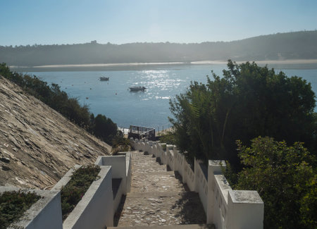 View of stairs leading to pier with small ferry boat across the river Mira flowing into the Atlantic...