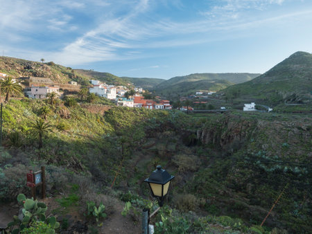 Early morning view of village Arure in green valley with palm trees and traditional colorful houses. Valle Gran Rey, La Gomera, Canary Islands, Spain, Europe. Blue sky white clouds backgroundの写真素材