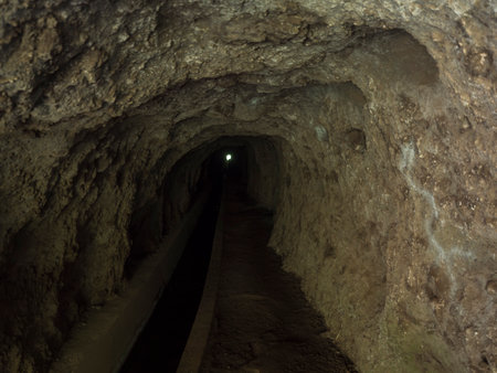 View through tunnel of levada, water irrigation channel at hiking trail Levada do moinho to levada...