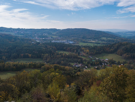 Panoramic view from viewpoint Stredni vrch near Dolni Prysk, Ceska Kamenice. Autumn landscape with colorful forest, hills and blue cloudy sky in Luzicke hory Lusatian Mountains, Czech Republic.の写真素材