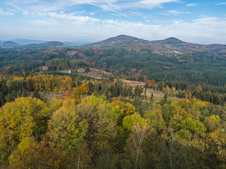 Panoramic view from viewpoint Stredni vrch near Dolni Prysk, Ceska Kamenice. Autumn landscape with colorful forest, hills and blue cloudy sky in Luzicke hory Lusatian Mountains, Czech Republic.の写真素材
