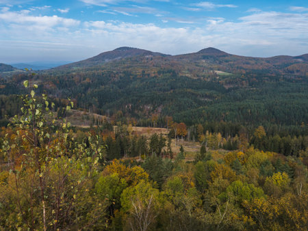 Panoramic view from viewpoint Stredni vrch near Dolni Prysk, Ceska Kamenice. Autumn landscape with colorful forest, hills and blue cloudy sky in Luzicke hory Lusatian Mountains, Czech Republic.の写真素材